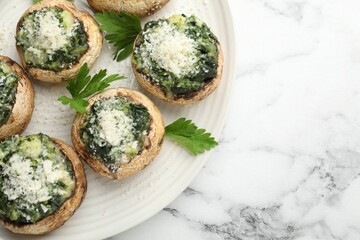 Tasty stuffed mushrooms served on white marble table, top view. Space for text