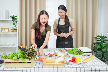 Two asian woman study online in the classroom making sandwich together in the home kitchen. Homemade and Learn online concept