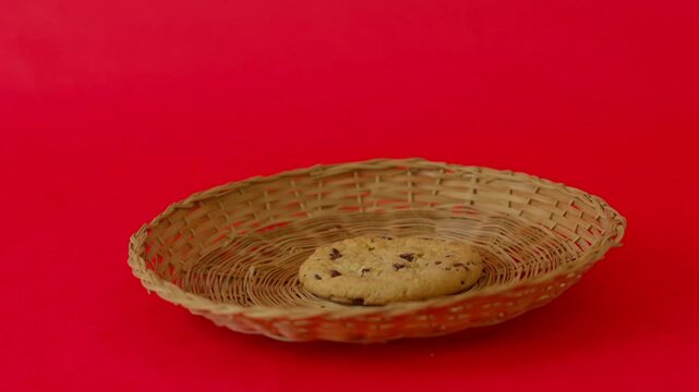 A cookie sits in a basket on a red background