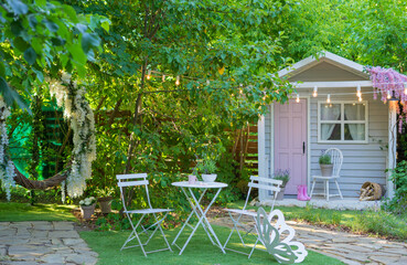 Cozy garden shed with lavender, pink rain boots, and fairy lights in a lush green backyard.