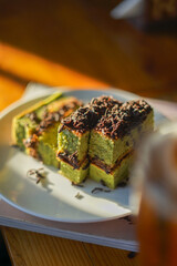 Matcha chocolate roll cake, Dessert made from green tea and chocolate blend with grated chocolate topping. Sliced ​​into squares on a plate