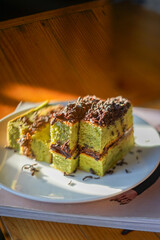 Matcha chocolate roll cake, Dessert made from green tea and chocolate blend with grated chocolate topping. Sliced ​​into squares on a plate