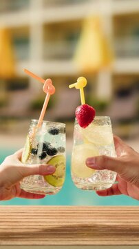 Fruit cocktail in hotel bar, Two cocktail glasses cheers in the hands on sea background. Bartenter making drink in bar, Summer vacation concept, A beautiful couple enjoy the vacation at the beach.