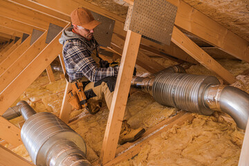 Contractor Working on HVAC Installation in Attic During Daylight