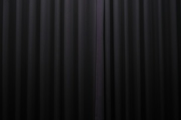 Close-up view of a black pleated curtain with subtle lighting