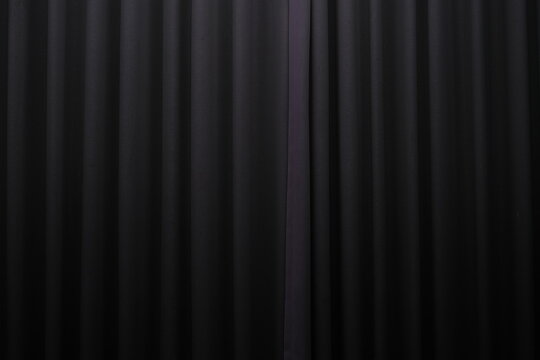 Close-up view of a black pleated curtain with subtle lighting