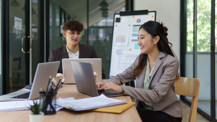 Two young businesspeople collaborating and discussing data insights in a modern office.