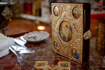 golden gospel cross and other church utensils on a church table in an Orthodox church, preparation...