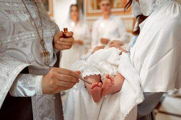 A priest anoints a baby's feet with oil during an Orthodox baptism