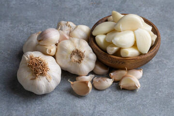 Garlic cloves in a glass bowl with peeled garlic