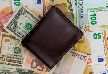 Brown leather wallet lies on banknotes