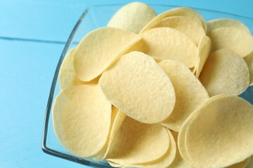 Tasty potato chips on blue wooden table, closeup