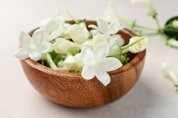 Bowl with jasmine flowers on beige table, closeup