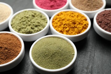Different superfood powders on black table, closeup