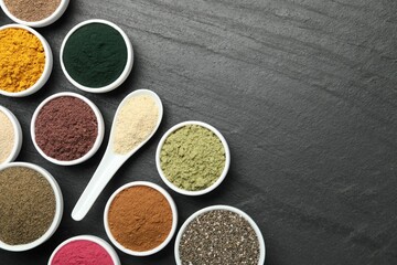 Different superfood powders on black table, flat lay. Space for text