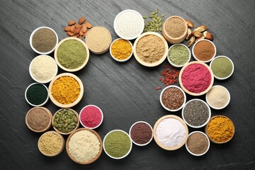 Frame of different superfood powders on black table, flat lay. Space for text