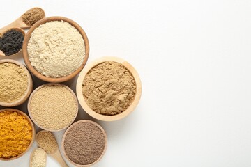 Different superfood powders in bowls and spoons on white background, flat lay. Space for text