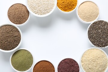 Frame of different superfood powders in bowls on white background, flat lay. Space for text
