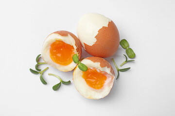 Soft boiled eggs with microgreens on white background, top view