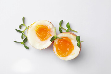 Soft boiled eggs with microgreens on white background, top view