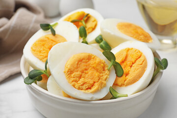 Halves of hard boiled eggs with microgreens on white table, closeup