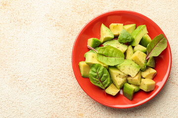 Tasty cut avocados with spinach and dressing on light textured table, top view. Space for text