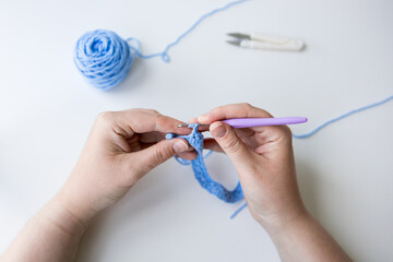 Close up of caucasian female crocheting blue yarn with hook in hand