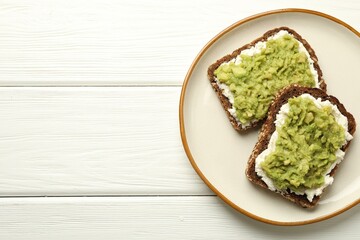 Delicious sandwiches with avocado and cream cheese on white wooden table, top view. Space for text