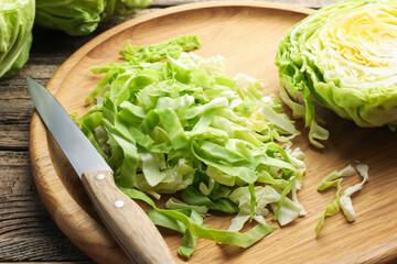 Cut fresh cabbage and knife on wooden table, closeup