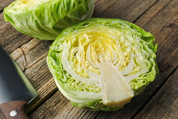 Halves of fresh cabbage and knife on wooden table, closeup