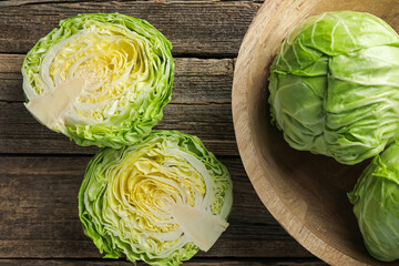 Obraz premium Fresh whole and cut cabbages on wooden table, flat lay