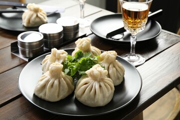 Delicious khinkali served with cilantro on wooden table, closeup