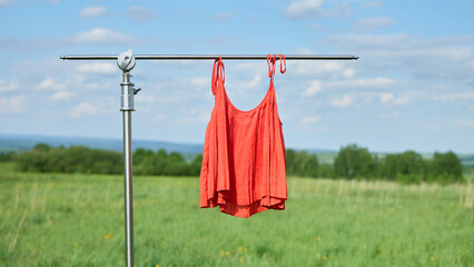 Summer dress hanging on a clothesline in a sunny field