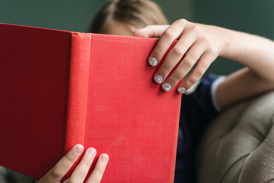 Book in child's hand with "hope" written on the nails