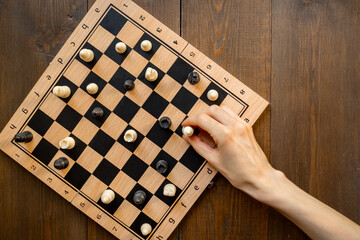 Hand is holding chess piece on chessboard. Game concept
