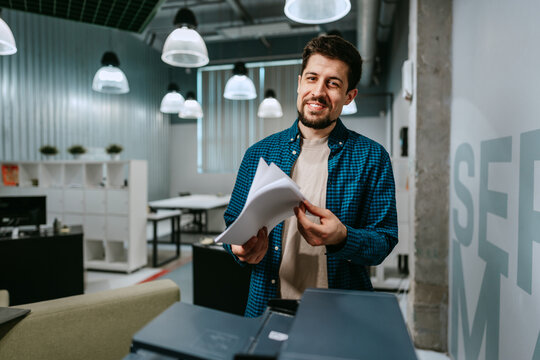 Smiling man organizing documents in a modern office space during the afternoon