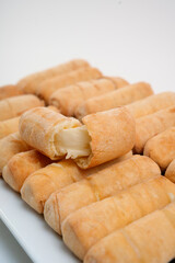 Tequeños cheese sticks showing filling on white background