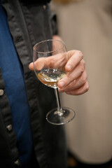 Man holding glass of white wine at a social event