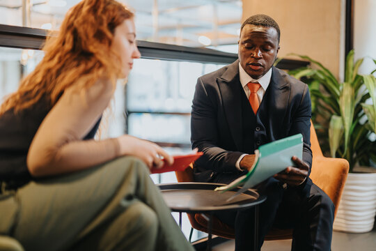 Two people collaborate in a modern office, discussing documents and ideas. Business attire and a contemporary atmosphere underscore a productive workplace interaction.