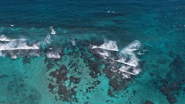 Drone image capturing the textured movement of ocean waves hitting the beach. The white foam patterns and symmetry of the water create a visually captivating natural scene.