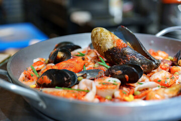Fresh seafood paella with shrimp, mussels, and squid served in a traditional pan at a coastal restaurant during dinner time