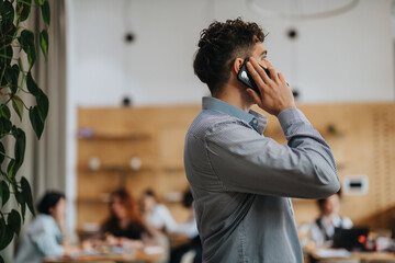 Professional man having a phone call, emphasizing communication and business in a cozy co working...