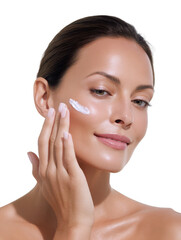 A beautiful woman applies skincare lotion to her face with her fingertips in front of a clean white background to moisturize and nourish her skin, radiating health.