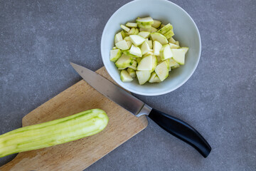 peeled and diced zucchini with knife on cutting board and in white bowl