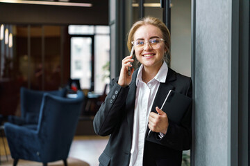 Confident businesswoman engaging in a phone conversation while standing in an elegant office space