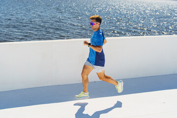 Running along the waterfront at sunset in vibrant activewear with joyful determination and energy
