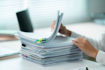 Businesswoman searching through a large stack of paperwork using binder clips in a bright office