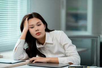 Young office worker experiencing burnout and fatigue while working with laptop
