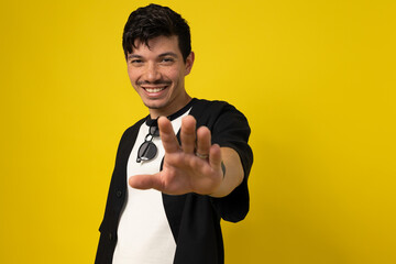 Young freckled man with a mustache posing with his hand extended in front on a yellow background...