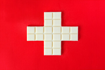 Swiss flag cross in form of white chocolate over the red background